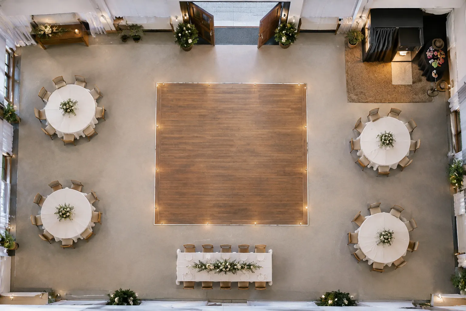 Bovenaanzicht van een trouwzaal met tafels, centrale dansvloer, open deur en photobooth in de rechterbovenhoek